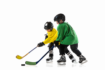 Image showing Little hockey players with the sticks on ice court and white studio background