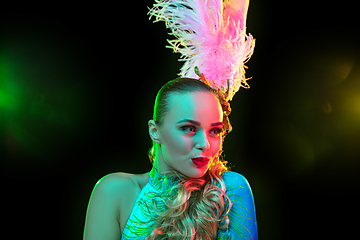 Image showing Beautiful young woman in carnival and masquerade costume in colorful neon lights on black background