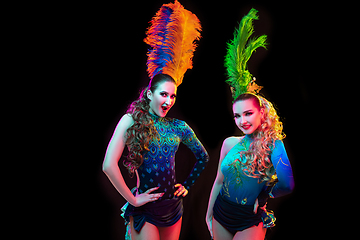 Image showing Beautiful young women in carnival and masquerade costume in colorful neon lights on black background