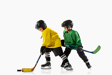 Image showing Little hockey players with the sticks on ice court and white studio background