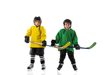 Image showing Little hockey players with the sticks on ice court and white studio background