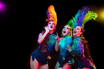 Image showing Beautiful young women in carnival and masquerade costume in colorful neon lights on black background