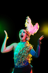 Image showing Beautiful young woman in carnival and masquerade costume in colorful neon lights on black background