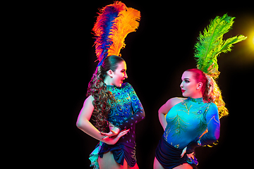 Image showing Beautiful young women in carnival and masquerade costume in colorful neon lights on black background