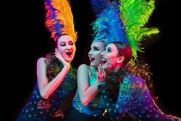 Image showing Beautiful young women in carnival and masquerade costume in colorful neon lights on black background