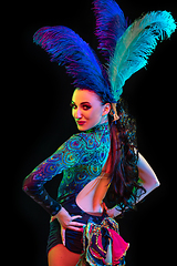 Image showing Beautiful young woman in carnival and masquerade costume in colorful neon lights on black background