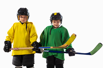 Image showing Little hockey players with the sticks on ice court and white studio background