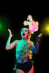 Image showing Beautiful young woman in carnival and masquerade costume in colorful neon lights on black background