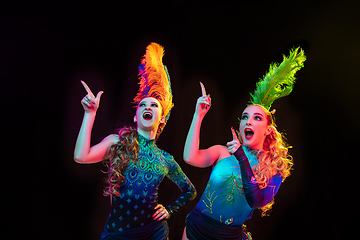 Image showing Beautiful young women in carnival and masquerade costume in colorful neon lights on black background