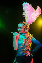 Image showing Beautiful young woman in carnival and masquerade costume in colorful neon lights on black background