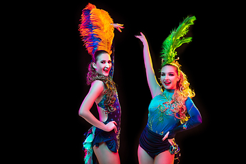 Image showing Beautiful young women in carnival and masquerade costume in colorful neon lights on black background