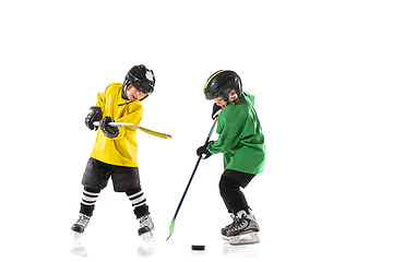 Image showing Little hockey players with the sticks on ice court and white studio background