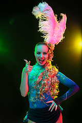 Image showing Beautiful young woman in carnival and masquerade costume in colorful neon lights on black background