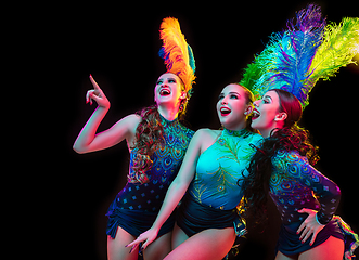 Image showing Beautiful young women in carnival and masquerade costume in colorful neon lights on black background