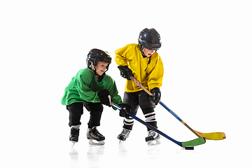 Image showing Little hockey players with the sticks on ice court and white studio background