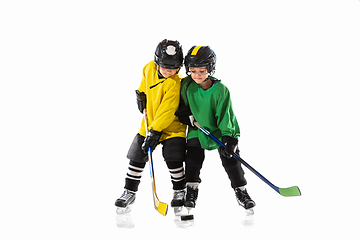 Image showing Little hockey players with the sticks on ice court and white studio background