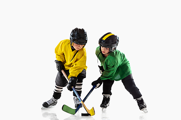 Image showing Little hockey players with the sticks on ice court and white studio background