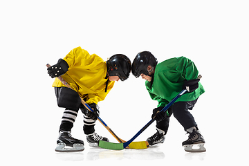 Image showing Little hockey players with the sticks on ice court and white studio background