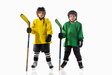 Image showing Little hockey players with the sticks on ice court and white studio background