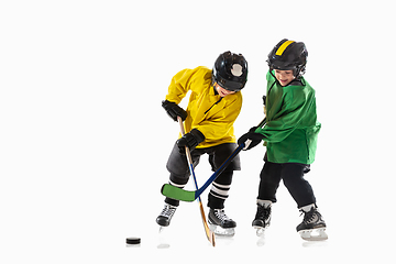 Image showing Little hockey players with the sticks on ice court and white studio background