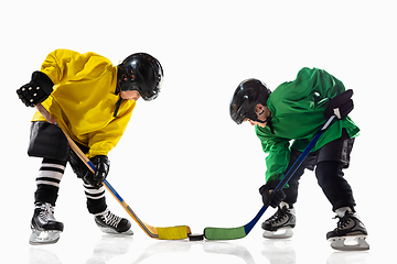 Image showing Little hockey players with the sticks on ice court and white studio background