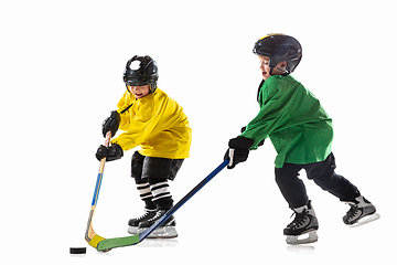 Image showing Little hockey players with the sticks on ice court and white studio background