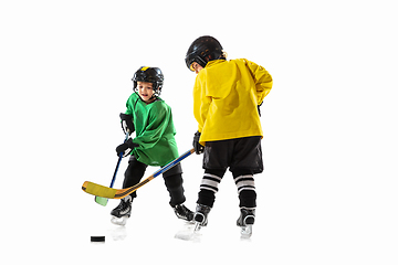 Image showing Little hockey players with the sticks on ice court and white studio background