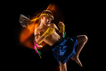 Image showing Little boy exercising thai boxing on black background. Fighter practicing, training in martial arts in action, motion. Evolution of movement, catching moment.