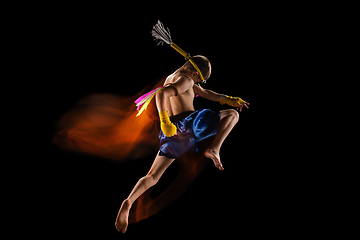 Image showing Little boy exercising thai boxing on black background. Fighter practicing, training in martial arts in action, motion. Evolution of movement, catching moment.