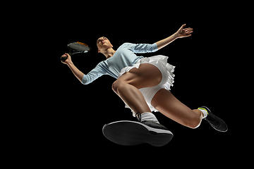 Image showing Female professional tennis player in action, motion isolated on black background, look from the bottom. Concept of sport, movement, energy and dynamic.
