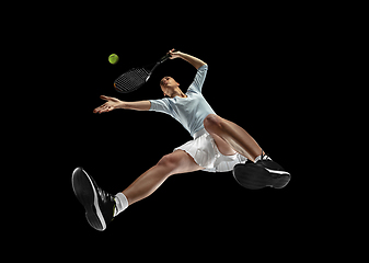 Image showing Female professional tennis player in action, motion isolated on black background, look from the bottom. Concept of sport, movement, energy and dynamic.