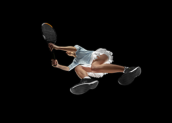 Image showing Female professional tennis player in action, motion isolated on black background, look from the bottom. Concept of sport, movement, energy and dynamic.