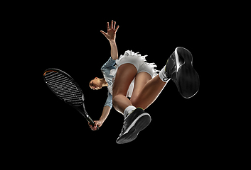 Image showing Female professional tennis player in action, motion isolated on black background, look from the bottom. Concept of sport, movement, energy and dynamic.