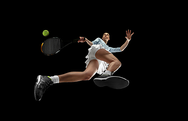 Image showing Female professional tennis player in action, motion isolated on black background, look from the bottom. Concept of sport, movement, energy and dynamic.