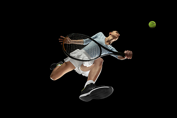 Image showing Female professional tennis player in action, motion isolated on black background, look from the bottom. Concept of sport, movement, energy and dynamic.