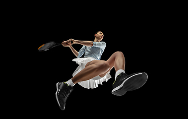 Image showing Female professional tennis player in action, motion isolated on black background, look from the bottom. Concept of sport, movement, energy and dynamic.