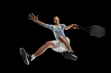 Image showing Female professional tennis player in action, motion isolated on black background, look from the bottom. Concept of sport, movement, energy and dynamic.