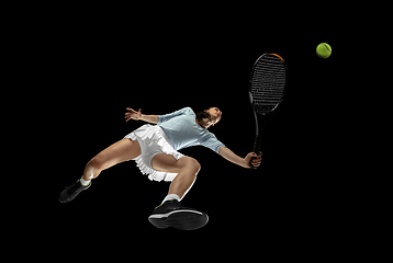 Image showing Female professional tennis player in action, motion isolated on black background, look from the bottom. Concept of sport, movement, energy and dynamic.