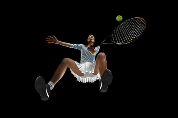 Image showing Female professional tennis player in action, motion isolated on black background, look from the bottom. Concept of sport, movement, energy and dynamic.