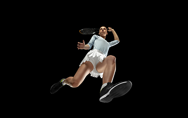 Image showing Female professional tennis player in action, motion isolated on black background, look from the bottom. Concept of sport, movement, energy and dynamic.