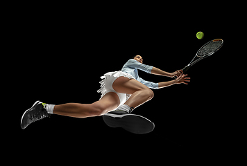 Image showing Female professional tennis player in action, motion isolated on black background, look from the bottom. Concept of sport, movement, energy and dynamic.