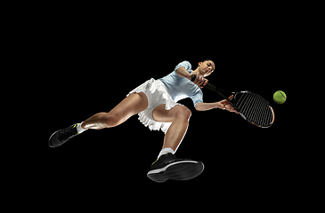 Image showing Female professional tennis player in action, motion isolated on black background, look from the bottom. Concept of sport, movement, energy and dynamic.