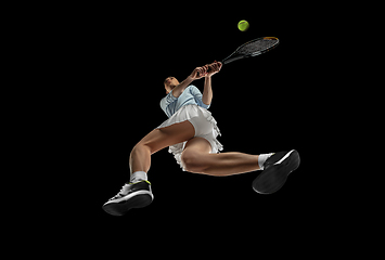 Image showing Female professional tennis player in action, motion isolated on black background, look from the bottom. Concept of sport, movement, energy and dynamic.