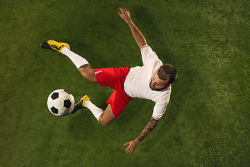 Image showing Top view of caucasian football or soccer player on green background of grass