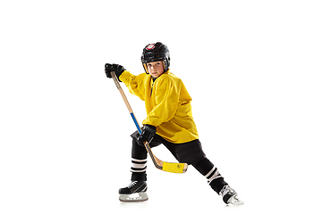 Image showing Little hockey player with the stick on ice court and white studio background