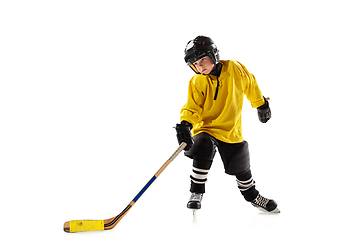 Image showing Little hockey player with the stick on ice court and white studio background