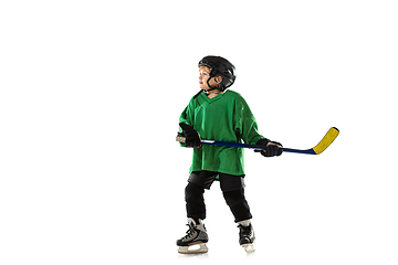 Image showing Little hockey player with the stick on ice court and white studio background