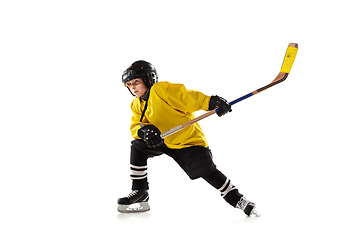 Image showing Little hockey player with the stick on ice court and white studio background