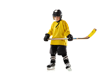 Image showing Little hockey player with the stick on ice court and white studio background