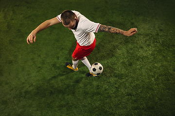 Image showing Top view of caucasian football or soccer player on green background of grass